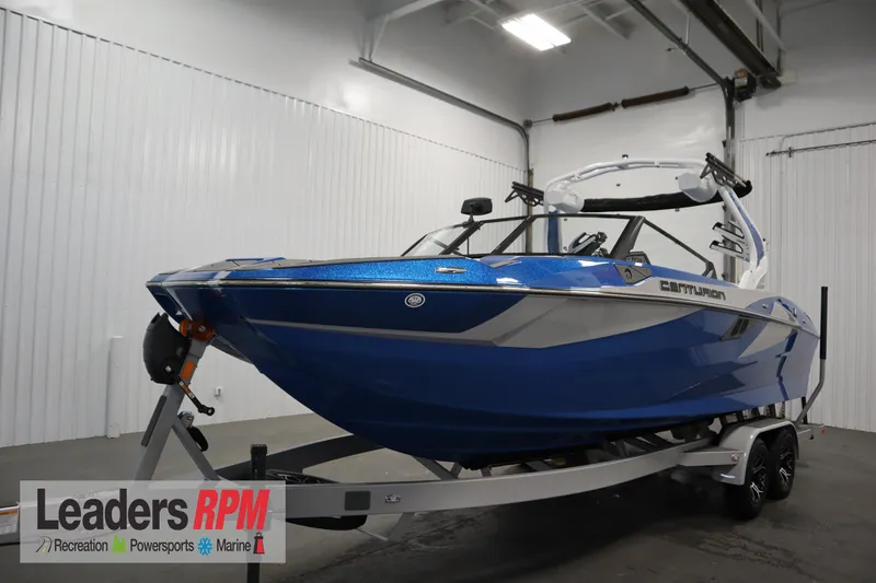 The Image of 2025 Centurion Fe23 boat in showroom, blue exterior, on trailer, Leaders RPM logo visible. - 1