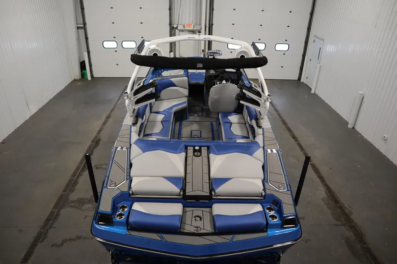 Slide: The Image of 2025 Centurion Fe23 boat interior with blue and gray seating, in a garage setting. - 10