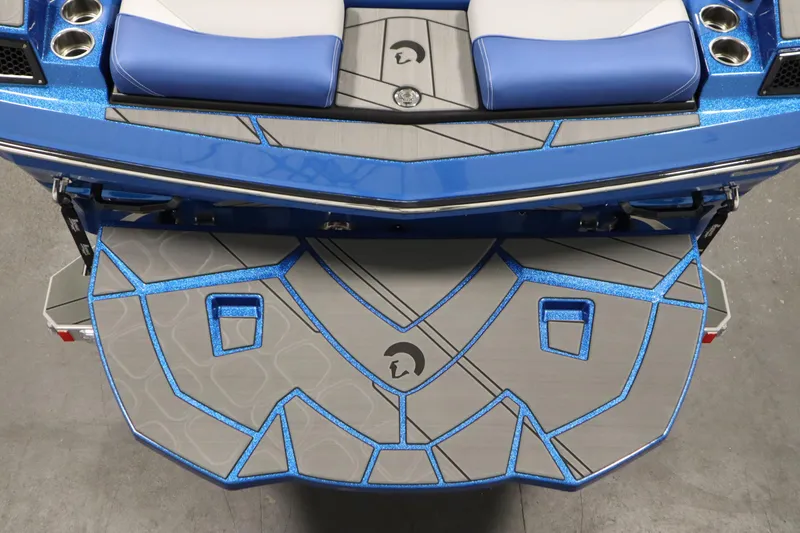 Slide: The Image of 2025 Centurion Fe23 boat with blue and gray deck design, featuring cup holders and seating. - 11