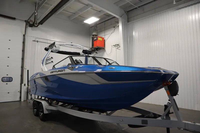 Slide: The Image of 2025 Centurion Fe23 boat in a garage, blue exterior, on a trailer. - 3