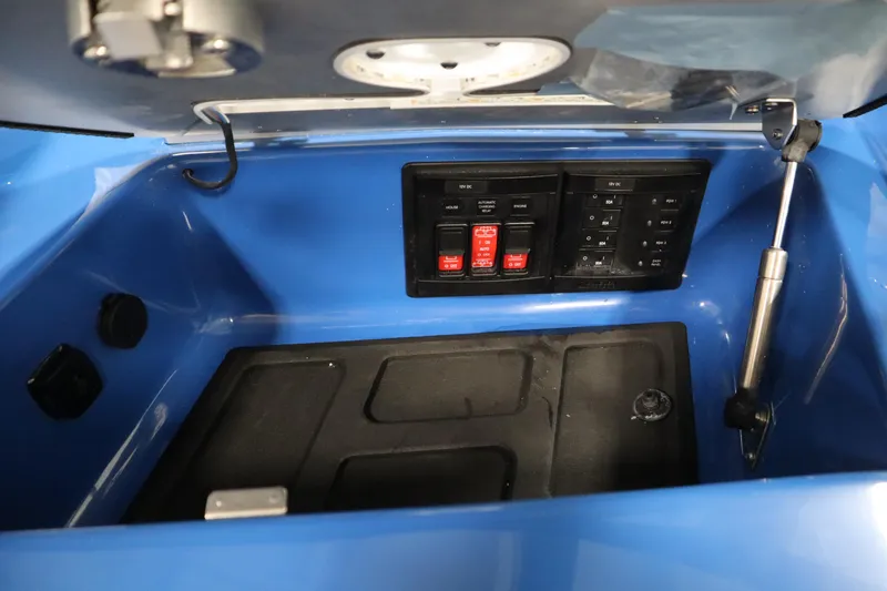 Slide: The Image of Control panel inside a 2025 Centurion Fe23 boat, featuring switches and storage compartment. - 35