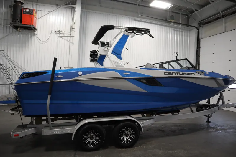 Slide: The Image of 2025 Centurion Fe23 boat in a garage, blue and white design on a trailer. - 4