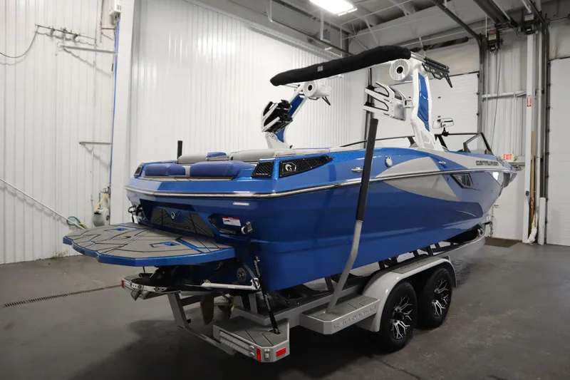 Slide: The Image of 2025 Centurion Fe23 boat in a garage, blue and white design, on a trailer. - 5