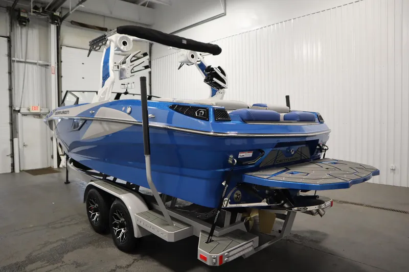 Slide: The Image of 2025 Centurion Fe23 boat in a garage, blue and white design, on a trailer. - 7