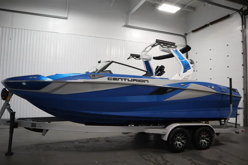 Slide: The Image of 2025 Centurion Fe23 boat in blue on a trailer, displayed indoors. - 8