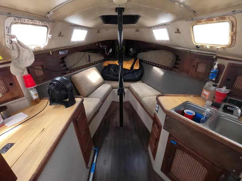 Slide: The Image of Interior of a 1984 Lancer 30 sailboat with cozy seating and compact kitchen area. - 10