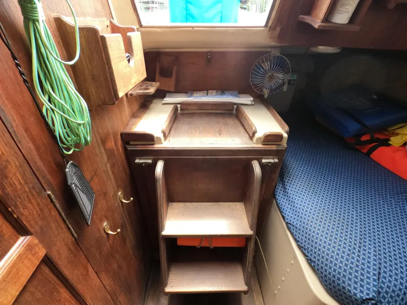 Slide: The Image of Interior of a 1984 Lancer 30 sailboat with wooden cabinetry and blue bedding. - 23