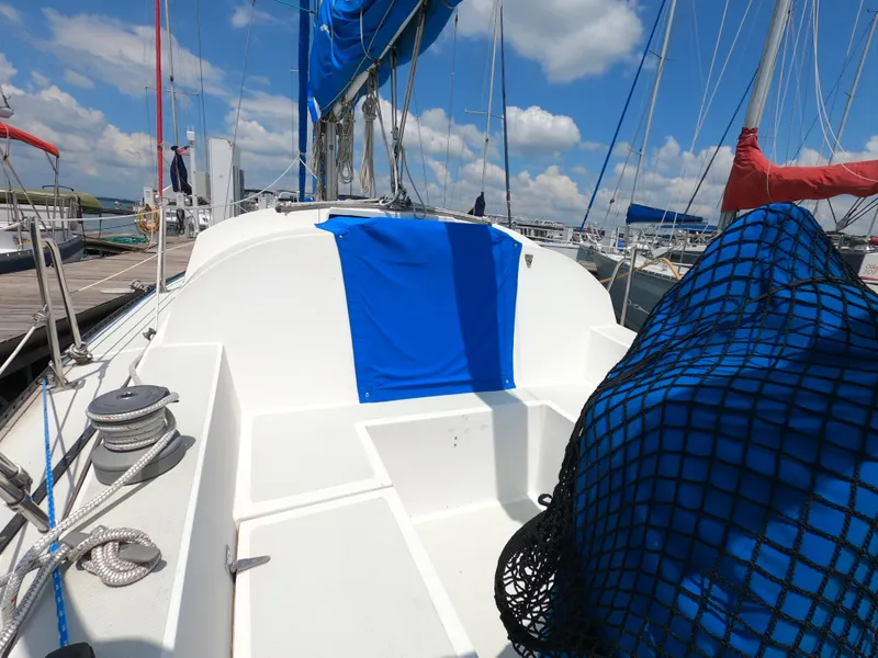 Slide: The Image of Sailboat deck of 1984 Lancer 30 with blue and red sails, docked at marina. - 4
