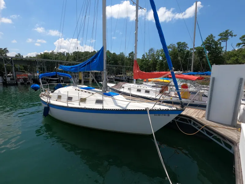 The Image of 1984 Lancer 30 sailboat docked at marina, blue and white design, clear sky background. - 0
