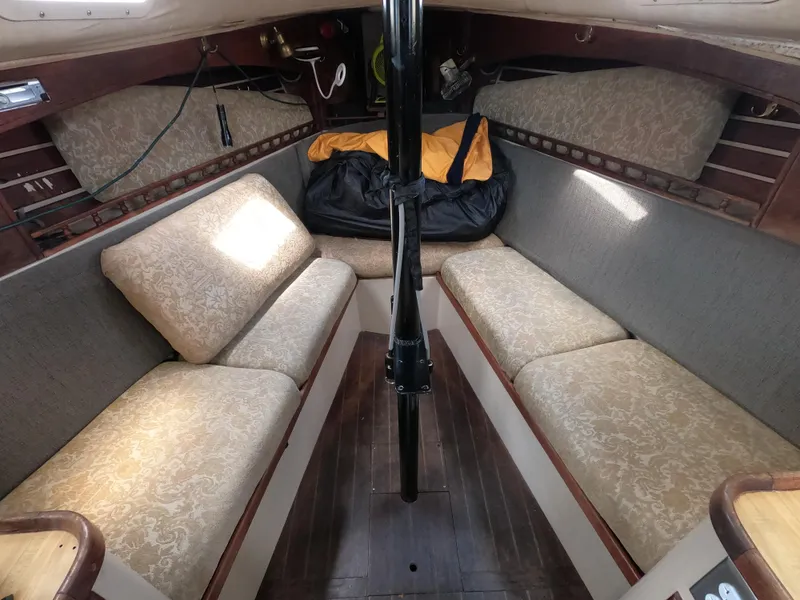 Slide: The Image of Interior of a 1984 Lancer 30 sailboat with cushioned seating and wooden flooring. - 11