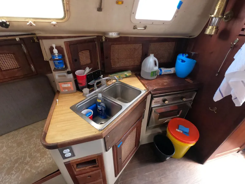 Slide: The Image of Compact kitchen area in a 1984 Lancer 30 sailboat with sink, stove, and storage. - 13