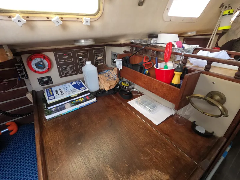 Slide: The Image of 1984 Lancer 30 sailboat interior with navigation tools and equipment on a wooden desk. - 16