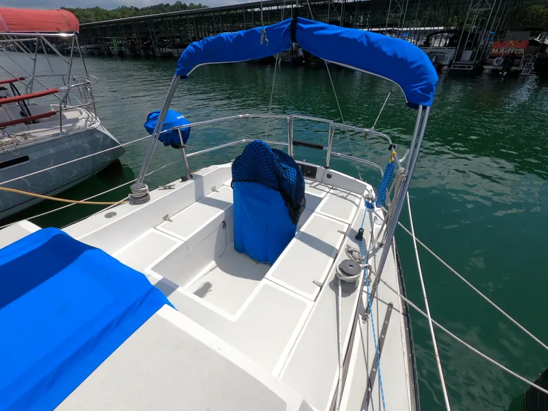Slide: The Image of 1984 Lancer 30 sailboat with blue covers docked on calm water. - 3
