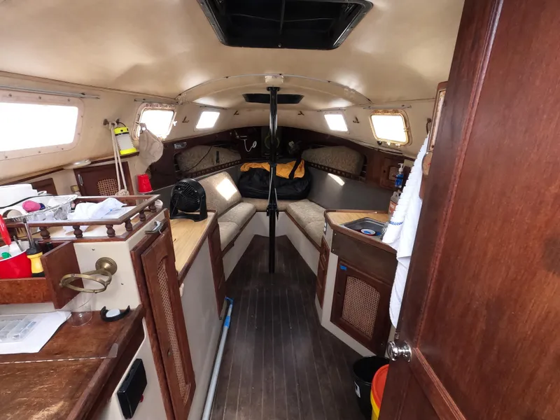 Slide: The Image of Interior of a 1984 Lancer 30 sailboat, featuring cozy seating and wooden cabinetry. - 9