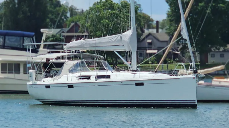 Slide: The Image of 2016 Hanse 415 sailboat docked in a marina, surrounded by trees and houses. - 0