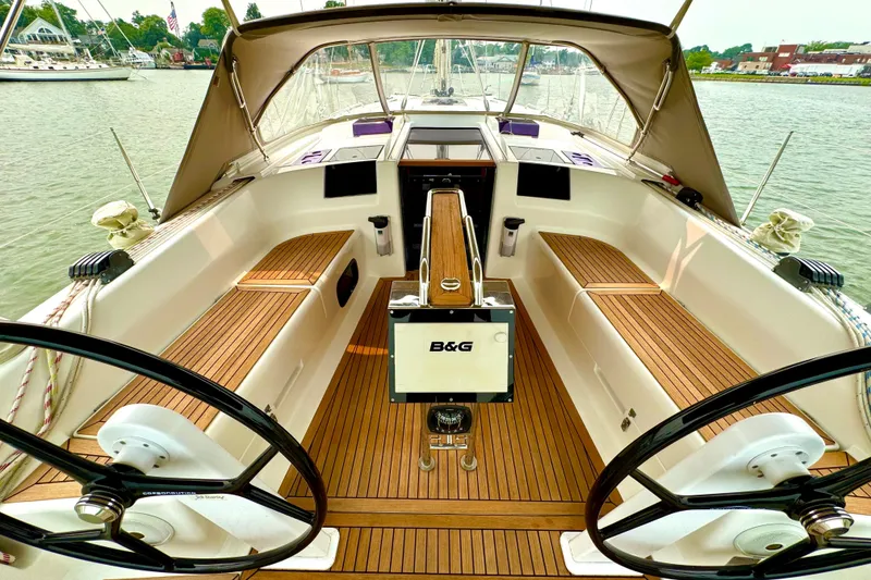 Slide: The Image of 2016 Hanse 415 yacht cockpit with dual steering wheels and teak flooring, docked by the water. - 6