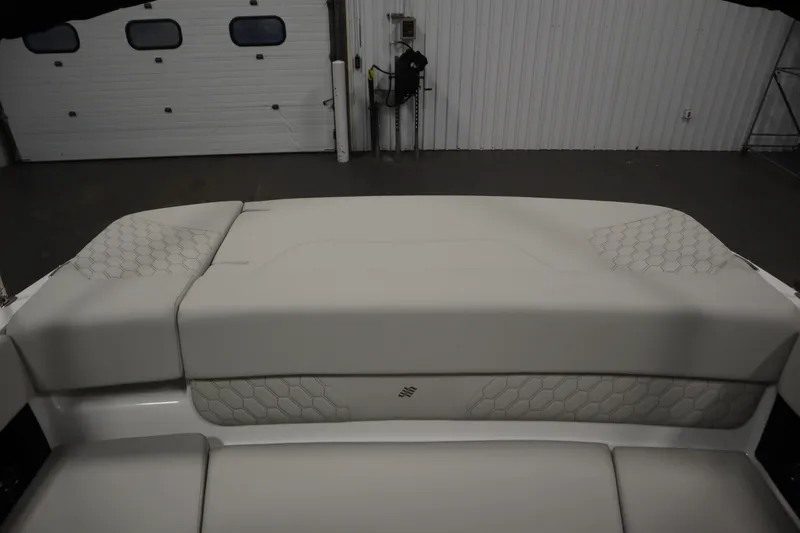 Slide: The Image of 2025 Four Winns H1 Freedom boat interior with cushioned seating in a garage setting. - 42