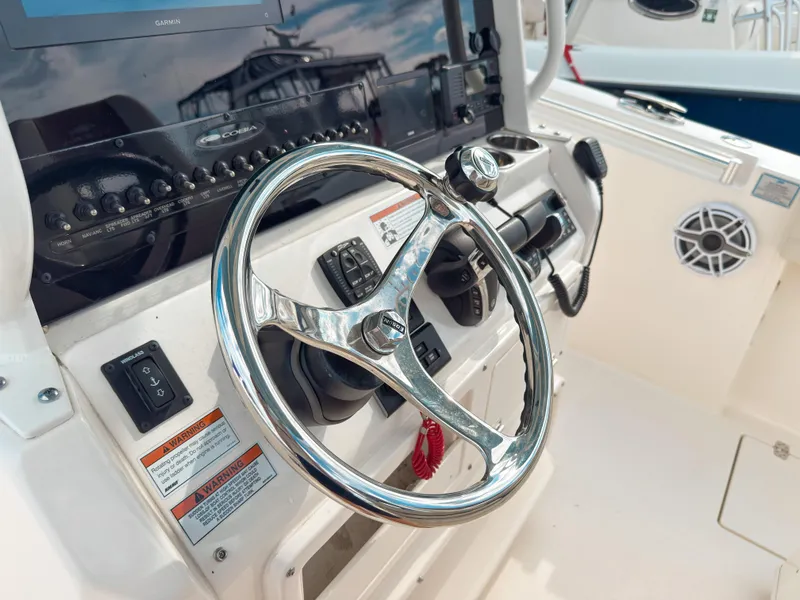 Slide: The Image of 2023 Cobia 280 Center Console helm with steering wheel and control panel. - 20