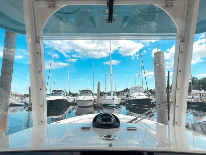 Slide: The Image of 2023 Cobia 280 Center Console boat docked in a marina with clear blue skies. - 23