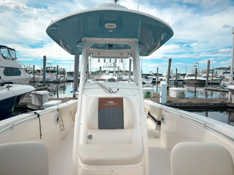 Slide: The Image of 2023 Cobia 280 Center Console boat docked at a marina under a blue sky. - 24