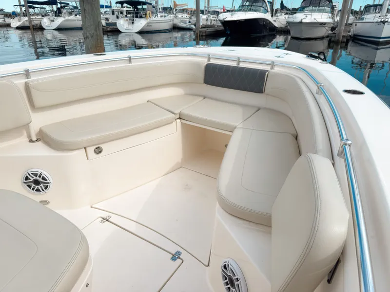 Slide: The Image of 2023 Cobia 280 Center Console boat interior with cushioned seating and speakers at a marina. - 30