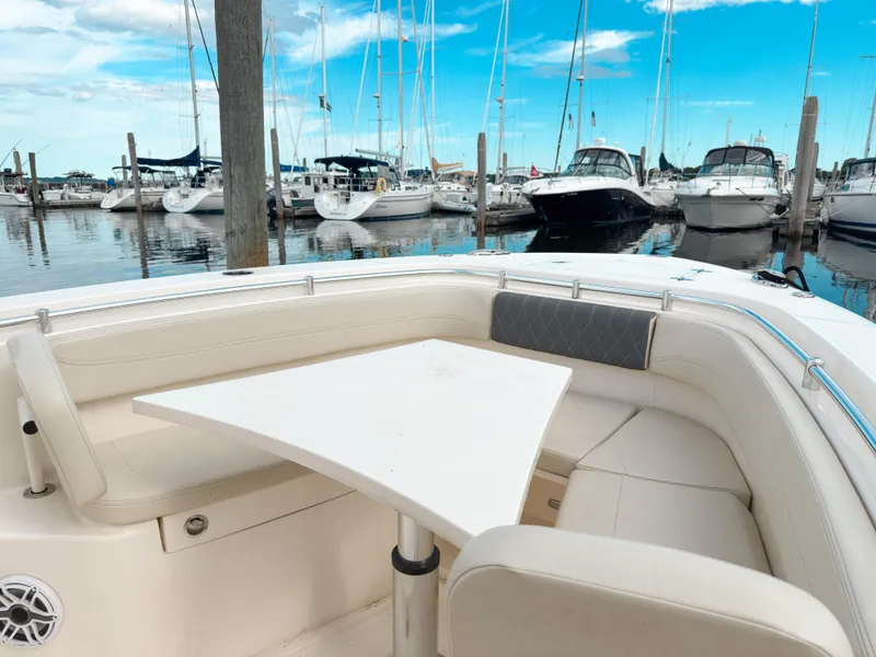 Slide: The Image of 2023 Cobia 280 Center Console boat interior with seating and table, docked at marina. - 31