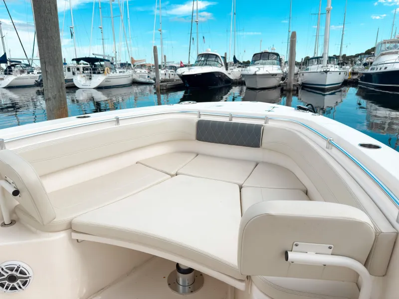 Slide: The Image of 2023 Cobia 280 Center Console boat with spacious seating in a marina setting. - 32