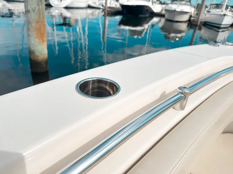 Slide: The Image of 2023 Cobia 280 Center Console boat detail with cup holder and railing, docked at marina. - 36
