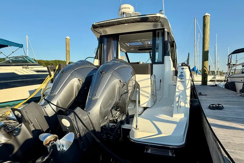 Slide: The Image of 2024 Jeanneau NC 1095 boat docked, featuring dual outboard engines and sleek design. - 14