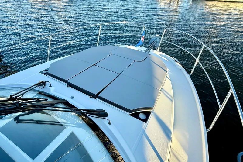 Slide: The Image of 2024 Jeanneau NC 1095 boat deck with sunpad, overlooking calm water. - 18