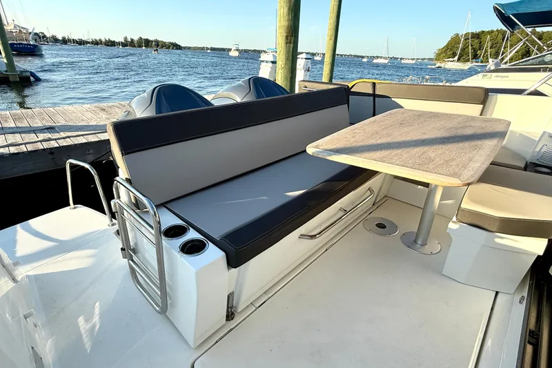 Slide: The Image of 2024 Jeanneau NC 1095 boat deck with seating and table, docked by the water. - 23
