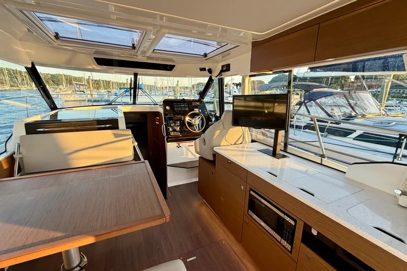 Slide: The Image of Interior of 2024 Jeanneau NC 1095 boat with modern helm, seating, and kitchen area. - 24
