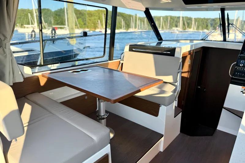 Slide: The Image of Interior of 2024 Jeanneau NC 1095 boat with seating and table, overlooking marina. - 28