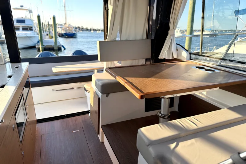 Slide: The Image of Interior of 2024 Jeanneau NC 1095 boat with dining area and marina view. - 29