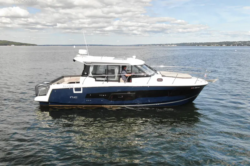 Slide: The Image of 2024 Jeanneau NC 1095 boat cruising on a calm lake under a partly cloudy sky. - 3