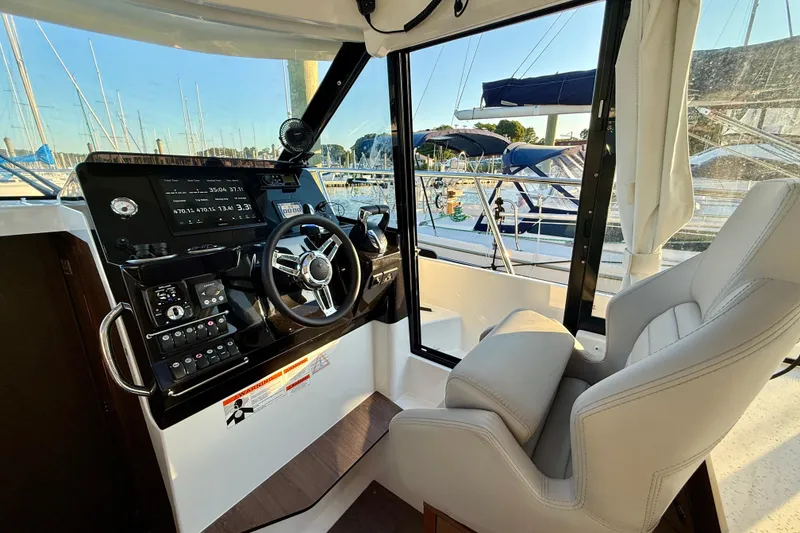 Slide: The Image of 2024 Jeanneau NC 1095 helm station with modern controls and marina view. - 34