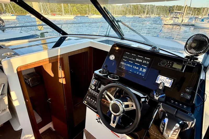 Slide: The Image of 2024 Jeanneau NC 1095 helm with modern controls and scenic marina view. - 35