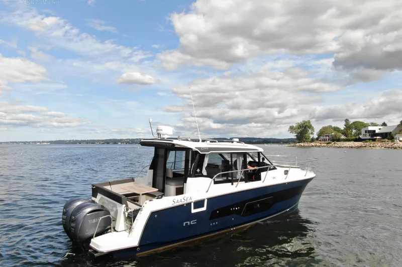 Slide: The Image of 2024 Jeanneau NC 1095 boat cruising on a calm lake under a partly cloudy sky. - 4