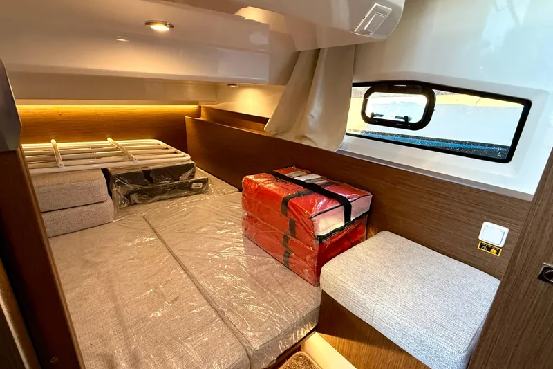 Slide: The Image of 2024 Jeanneau NC 1095 cabin interior with bed, window, and storage. - 41