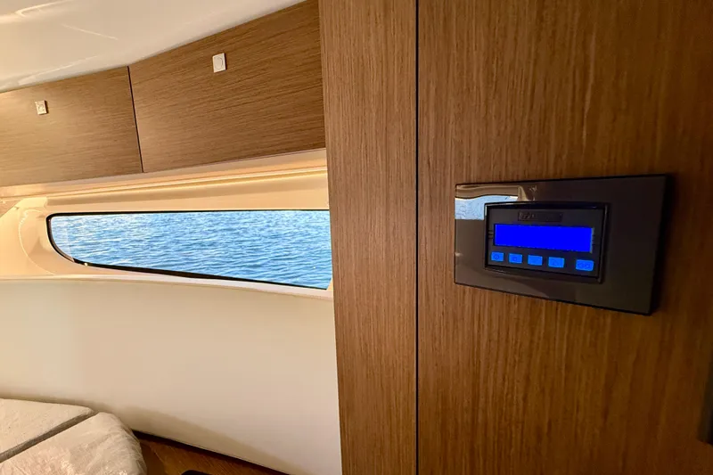 Slide: The Image of 2024 Jeanneau NC 1095 interior with wood paneling and digital control panel. - 43