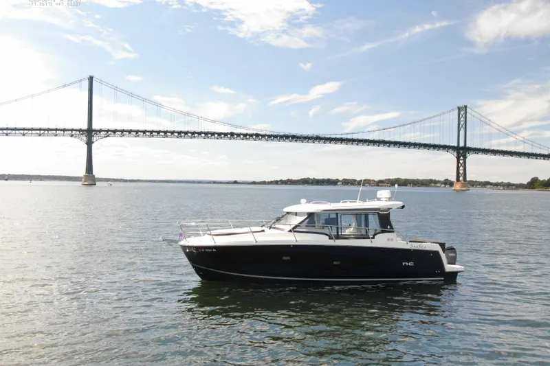 Slide: The Image of 2024 Jeanneau NC 1095 boat on water with bridge in background, under clear sky. - 5