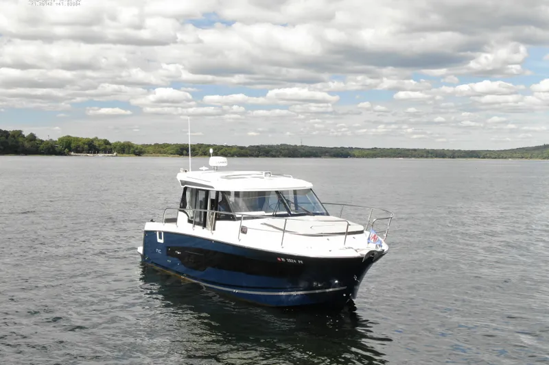 Slide: The Image of 2024 Jeanneau NC 1095 boat on calm water under a cloudy sky. - 9
