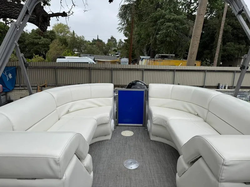 Slide: The Image of 2023 Frontier 24' Cruiser boat with white seating and blue door, outdoor setting. - 11