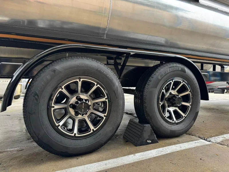 Slide: The Image of 2023 Frontier 24' Cruiser trailer wheels on pavement, featuring black and silver rims. - 30