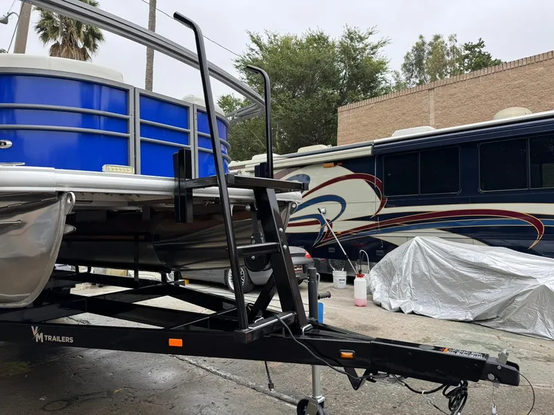 Slide: The Image of 2023 Frontier 24' Cruiser boat on trailer, parked beside an RV. - 37