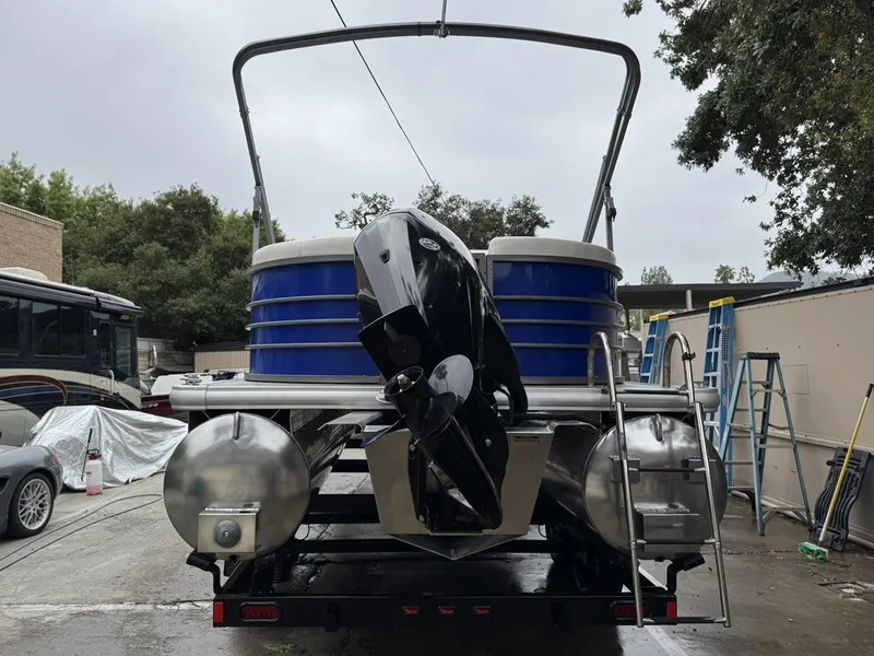 Slide: The Image of 2023 Frontier 24' Cruiser pontoon boat with outboard motor, parked outdoors. - 38