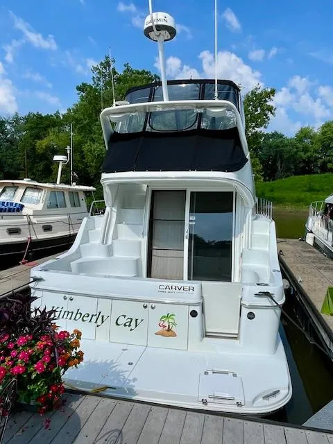 Slide: The Image of 2003 Carver 360 Sport Sedan docked, featuring "Kimberly Cay" name, surrounded by lush greenery. - 4