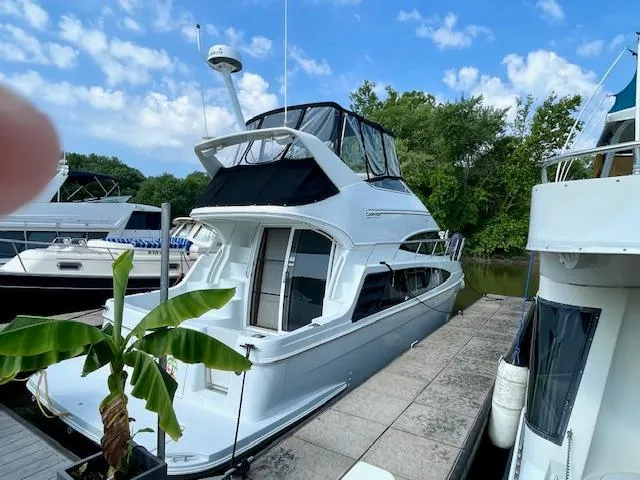 Slide: The Image of 2003 Carver 360 Sport Sedan docked, surrounded by lush greenery and other boats. - 5