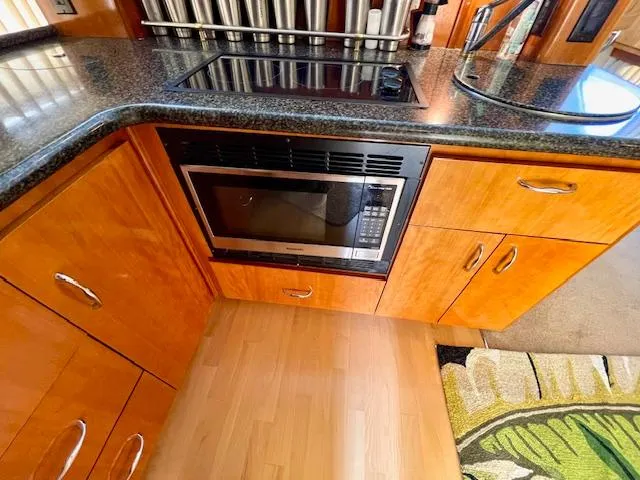 Slide: The Image of 2003 Carver 360 Sport Sedan kitchen with microwave, wooden cabinets, and black countertop. - 27