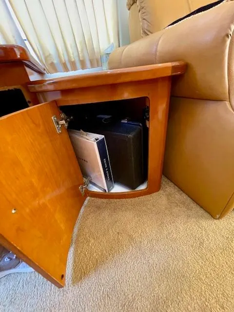 Slide: The Image of Open wooden cabinet in 2003 Carver 360 Sport Sedan, revealing storage with books and a briefcase. - 42